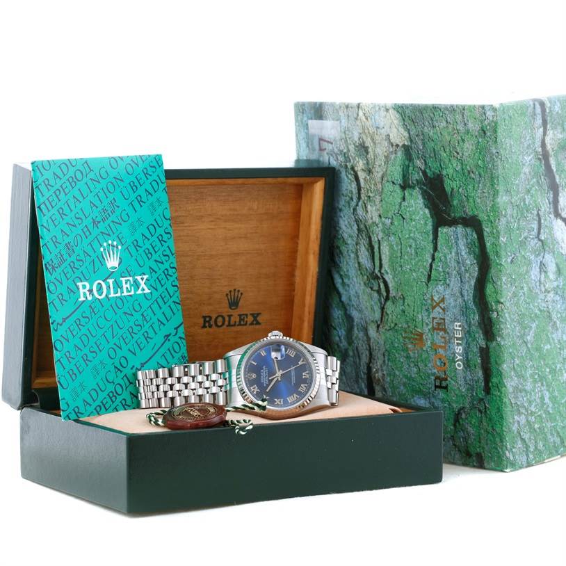 The Rolex Datejust 16234 Men's Stainless Steel Blue Dial 16234 Men's Stainless Steel Blue Dial is shown at an angled top view inside its open box, along with a booklet and additional accessories.