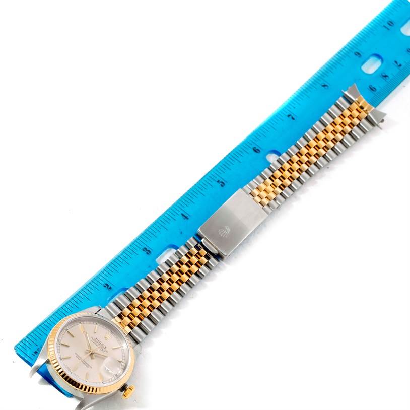 The image shows a Rolex Datejust 16233 Men's Steel and Gold (two tone) Silver Dial 16233 Men's Steel and Gold (two tone) Silver Dial watch laid flat next to a ruler, highlighting its two-tone bracelet and clasp.