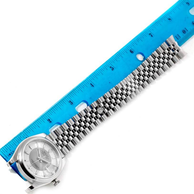 This image shows a side view of a Rolex Datejust 116200 Men's Stainless Steel Silver Dial 116200 Men's Stainless Steel Silver Dial watch and its bracelet, with a blue ruler for scale.