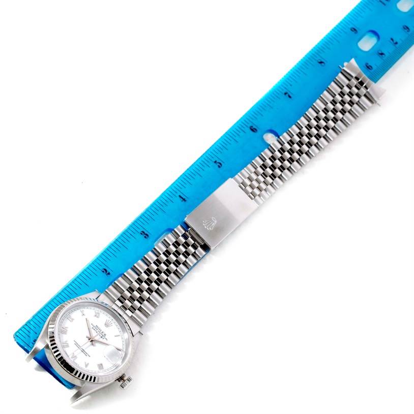The Rolex Datejust 16234 Men's Stainless Steel White Dial 16234 Men's Stainless Steel White Dial watch is displayed lying flat with its face and bracelet band visible, next to a blue ruler for size reference.