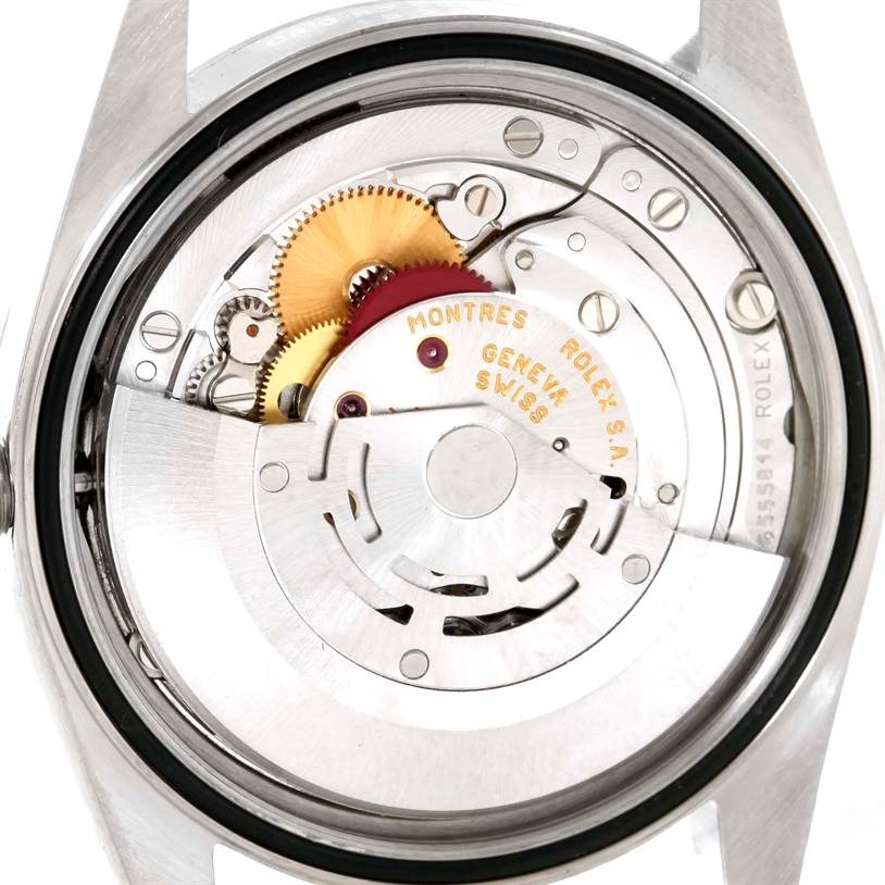 The image shows a close-up view of the movement mechanism inside a Rolex Datejust 16234 Men's Stainless Steel White Dial 16234 Men's Stainless Steel White Dial watch, highlighting gears and inscriptions.
