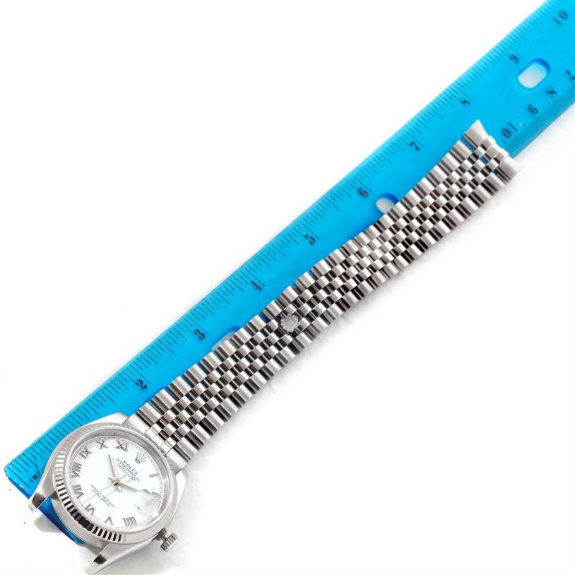 The Rolex Datejust 116234 Men's Stainless Steel White Dial 116234 Men's Stainless Steel White Dial watch is shown laying flat with a blue ruler measuring its bracelet length.