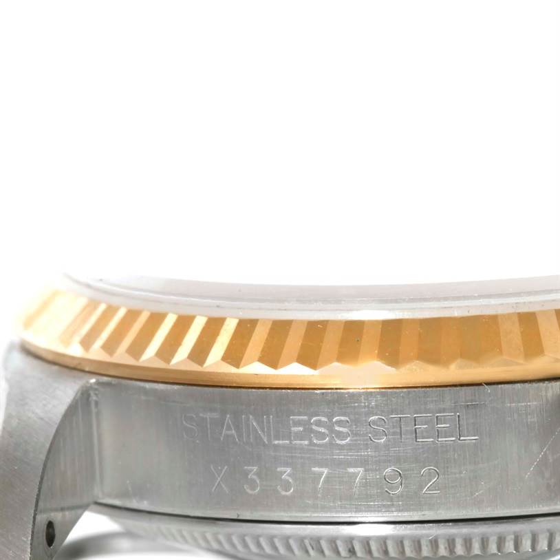 This close-up image of a Rolex Datejust 16233 Men's Steel and Gold (two tone) Beige Dial 16233 Men's Steel and Gold (two tone) Beige Dial watch shows its stainless steel side and fluted bezel with engraved serial number.