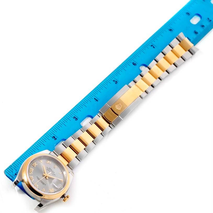 This image shows a Rolex Datejust 116203 Men's Stainless Steel Grey Dial 116203 Men's Stainless Steel Grey Dial watch laid alongside a blue ruler, highlighting the watch face and two-tone bracelet.