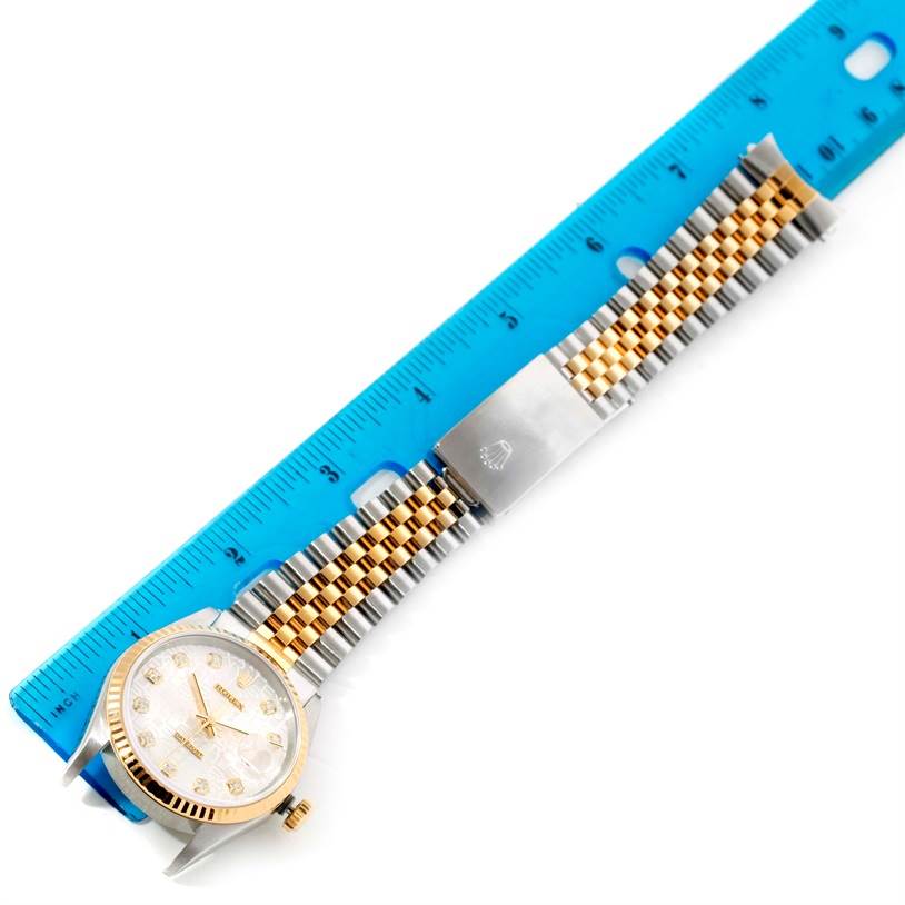 The Rolex Datejust 16233 Men's Steel and Gold (two tone) Silver Dial 16233 Men's Steel and Gold (two tone) Silver Dial watch is shown from a top-down angle with its face, case, and bracelet visible alongside a blue ruler.