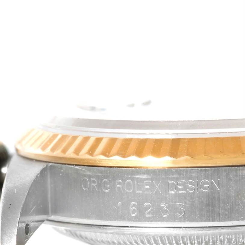 This close-up image of the Rolex Datejust 16233 Men's Steel and Gold (two tone) Black Dial 16233 Men's Steel and Gold (two tone) Black Dial watch shows the case side engraving and the fluted bezel.