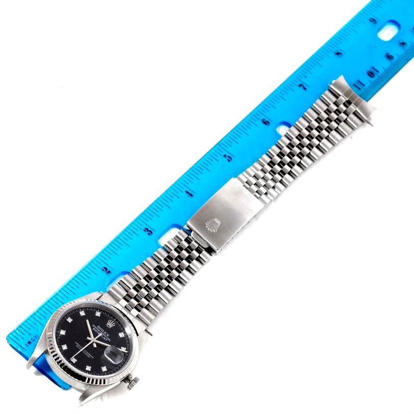 The image shows a Rolex Datejust 16234 Men
s Stainless Steel Black Dial 16234 Men
s Stainless Steel Black Dial watch laid flat with a blue ruler measuring its bracelet length.