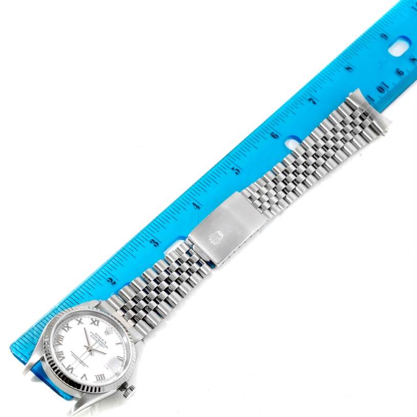 The image shows a horizontal view of a Rolex Datejust 16234 Men's Stainless Steel White Dial 16234 Men's Stainless Steel White Dial watch with a Jubilee bracelet, next to a blue ruler for scale.