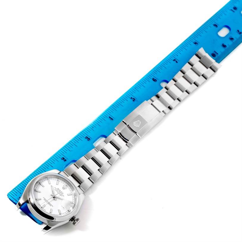 The image shows a top-down view of a Rolex Datejust 116200 Men's Stainless Steel Silver Dial 116200 Men's Stainless Steel Silver Dial watch with its bracelet extended alongside a blue ruler for measurement.