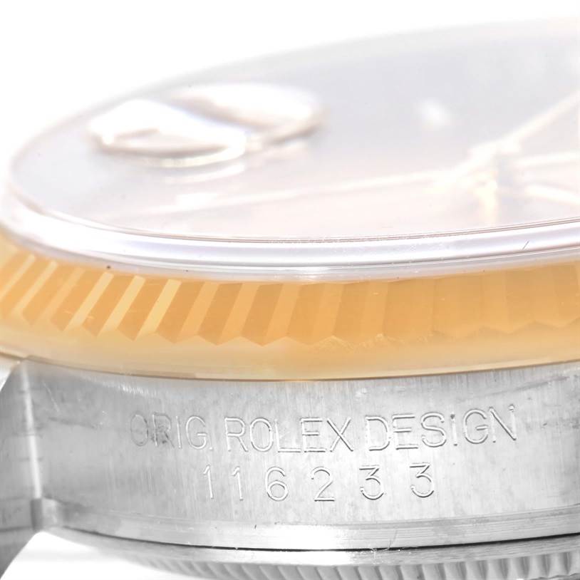 This close-up image of the Rolex Datejust 116233 Men's Stainless Steel Champagne Dial 116233 Men's Stainless Steel Champagne Dial shows the case side engraving and part of the fluted bezel.