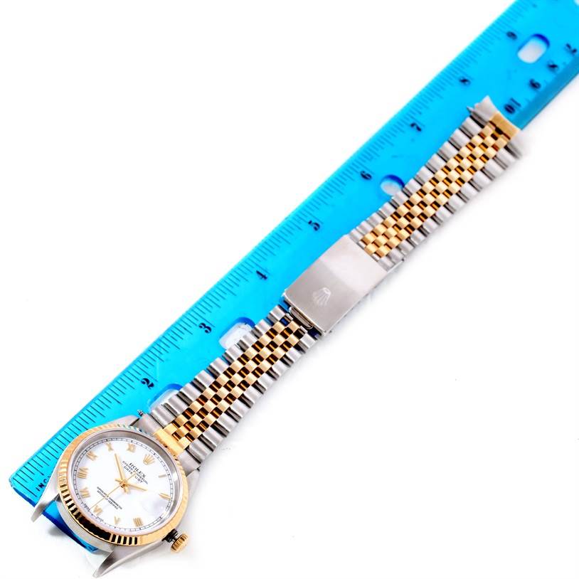 The image shows the Rolex Datejust 16233 Men's Steel and Gold (two tone) White Dial 16233 Men's Steel and Gold (two tone) White Dial watch laid flat beside a ruler, displaying its face, bracelet, and clasp.