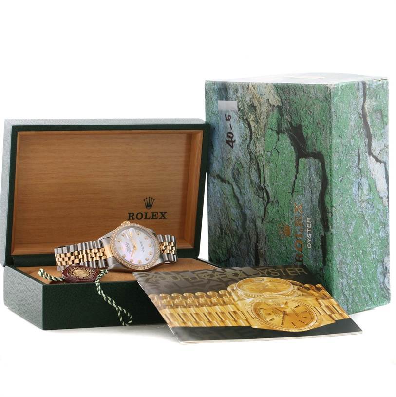 The image shows a Rolex Datejust 16233 Men
s Steel and Gold (two tone) Mother of Pearl Dial 16233 Men
s Steel and Gold (two tone) Mother of Pearl Dial watch in an open green box with a booklet and original packaging beside it.