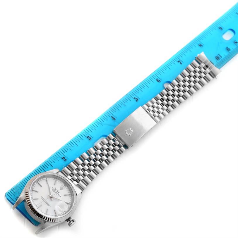 The image shows a horizontal view of a Rolex Datejust 16234 Men
s Stainless Steel White Dial 16234 Men
s Stainless Steel White Dial watch, highlighting its dial, crown, and metal bracelet, alongside a ruler.