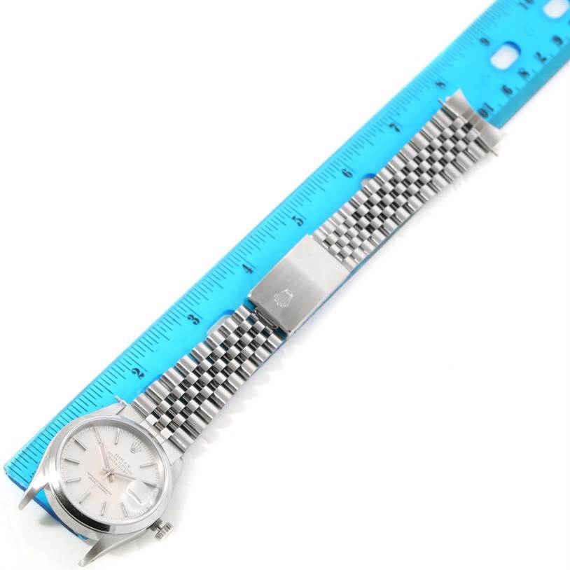 The Rolex Datejust 16200 Men's Stainless Steel Silver Dial 16200 Men's Stainless Steel Silver Dial watch is shown flat, face up, with its metal bracelet beside a blue ruler for scale.