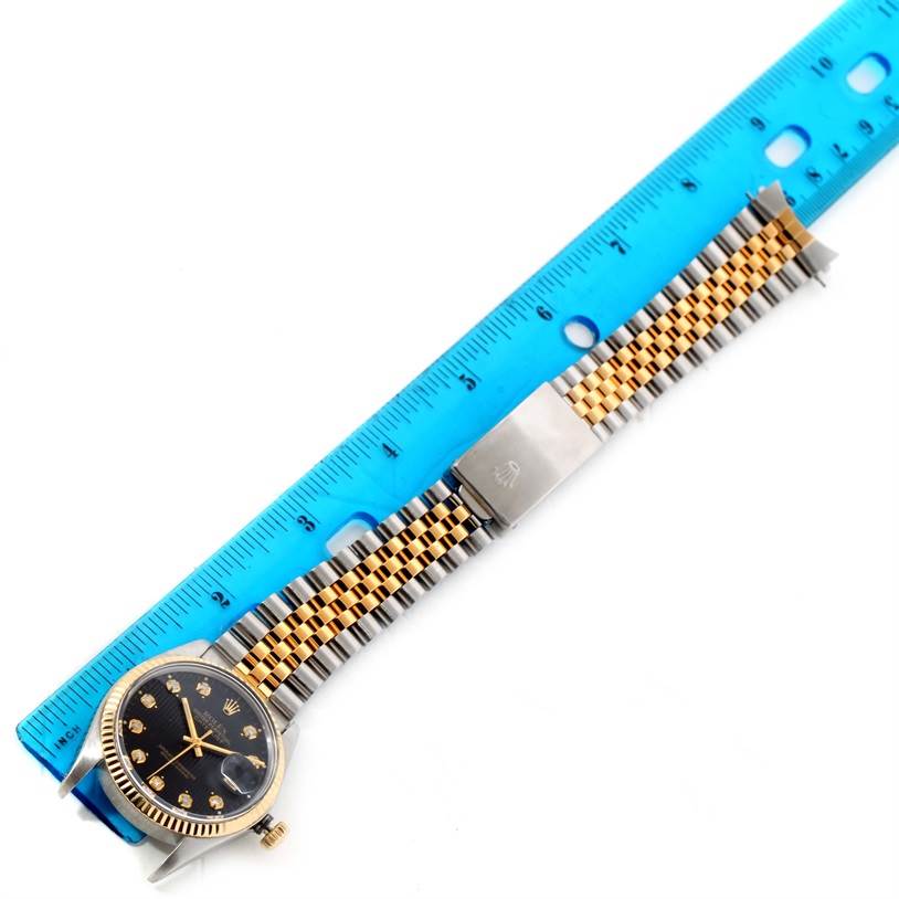 The Rolex Datejust 16013 Men
s Stainless Steel Black Dial 16013 Men
s Stainless Steel Black Dial watch is shown from a top-down angle with the face, bezel, and band clearly visible next to a ruler.