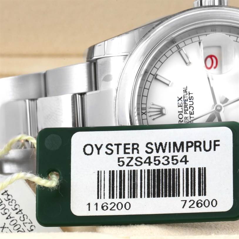 This image shows a partial view of the Rolex Datejust 116200WSO Men's Stainless Steel White Dial 116200WSO Men's Stainless Steel White Dial watch face and bracelet, along with an Oyster Swimpruf tag.