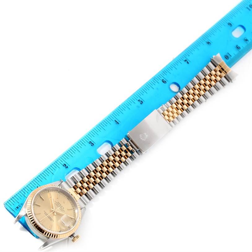 The image shows a Rolex Datejust 16233 Men's Steel and Gold (two tone) Champagne Dial 16233 Men's Steel and Gold (two tone) Champagne Dial watch laid flat next to a blue ruler, displaying its gold dial and jubilee bracelet.