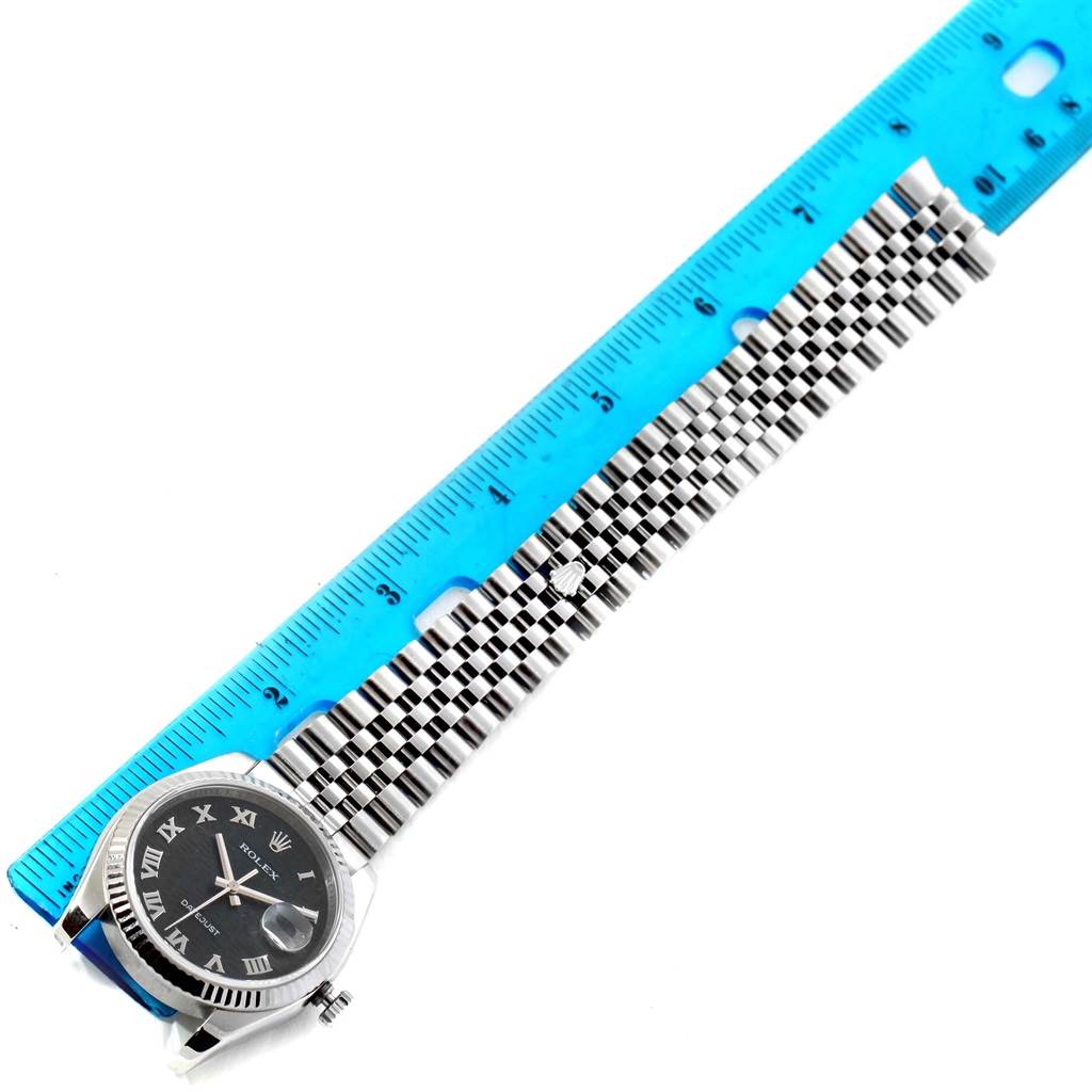 The image shows a Rolex Datejust 116234 Men's Stainless Steel Black Dial 116234 Men's Stainless Steel Black Dial watch laying flat, with a blue ruler measuring its bracelet length.