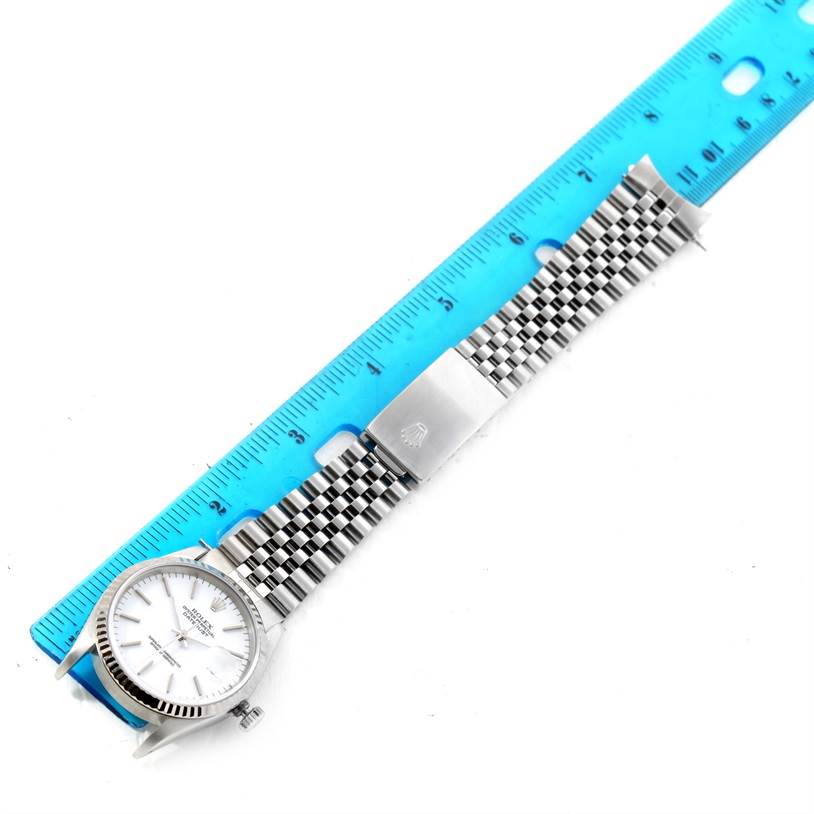 The image shows a Rolex Datejust 16234 Men's Stainless Steel White Dial 16234 Men's Stainless Steel White Dial watch laid flat with its full bracelet extended beside a blue ruler for scale.
