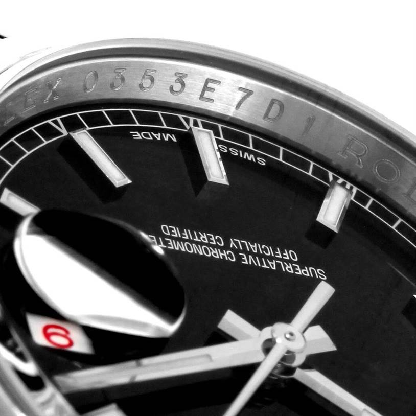 The image shows a close-up of the dial and part of the rehaut of a Rolex Datejust 116200BKSO Men's Stainless Steel Black Dial 116200BKSO Men's Stainless Steel Black Dial watch, highlighting its hands, indices, and engravings.