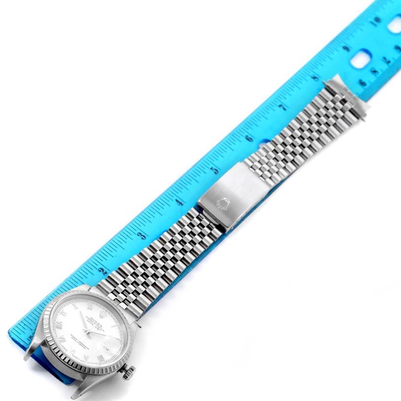 The image shows a top-down view of a Rolex Datejust 16220 Men's Stainless Steel White Dial 16220 Men's Stainless Steel White Dial watch including its face and metal bracelet alongside a measuring ruler.