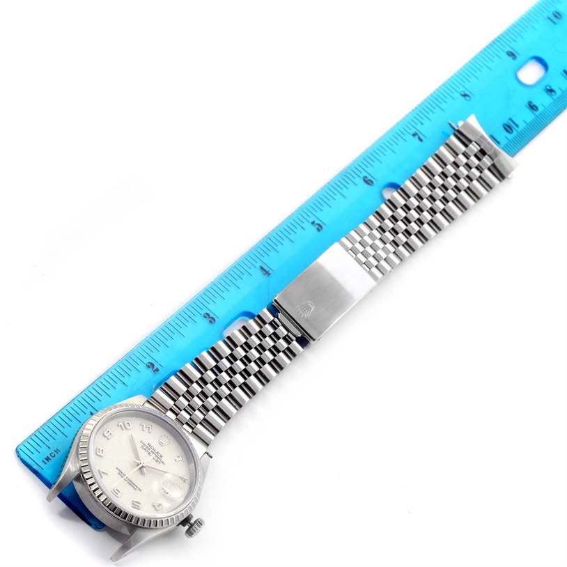 The image shows the Rolex Datejust 16220 Men's Stainless Steel Beige Dial 16220 Men's Stainless Steel Beige Dial watch laid flat next to a blue ruler, highlighting the dial, bezel, and metal bracelet.