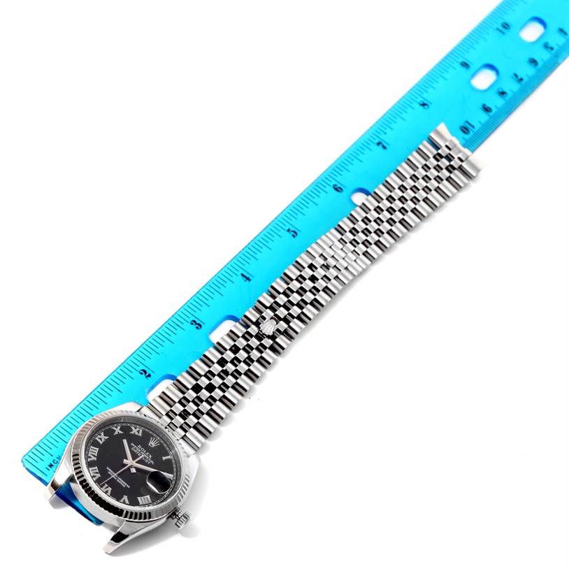 The image shows a Rolex Datejust 116234 Men
s Stainless Steel Black Dial 116234 Men
s Stainless Steel Black Dial watch lying flat with its bracelet and part of the dial visible next to a ruler for measurement.