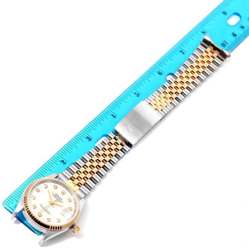 The image shows a Rolex Datejust 16233 Men's Steel and Gold (two tone) White Dial 16233 Men's Steel and Gold (two tone) White Dial watch laid flat next to a blue ruler, displaying the entire face and two-tone bracelet with clasp.