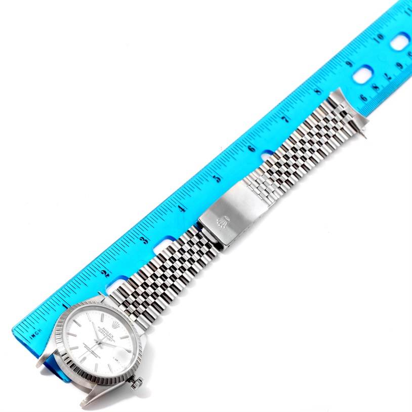 The image shows a Rolex Datejust 16220 Men's Stainless Steel White Dial 16220 Men's Stainless Steel White Dial watch horizontally, with the dial, aluminum bezel, and jubilee bracelet on display next to a ruler.