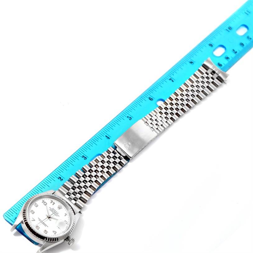 The Rolex Datejust 16234 Men's Stainless Steel White Dial 16234 Men's Stainless Steel White Dial watch is shown from an overhead angle, displaying the face and entire metal bracelet alongside a ruler.