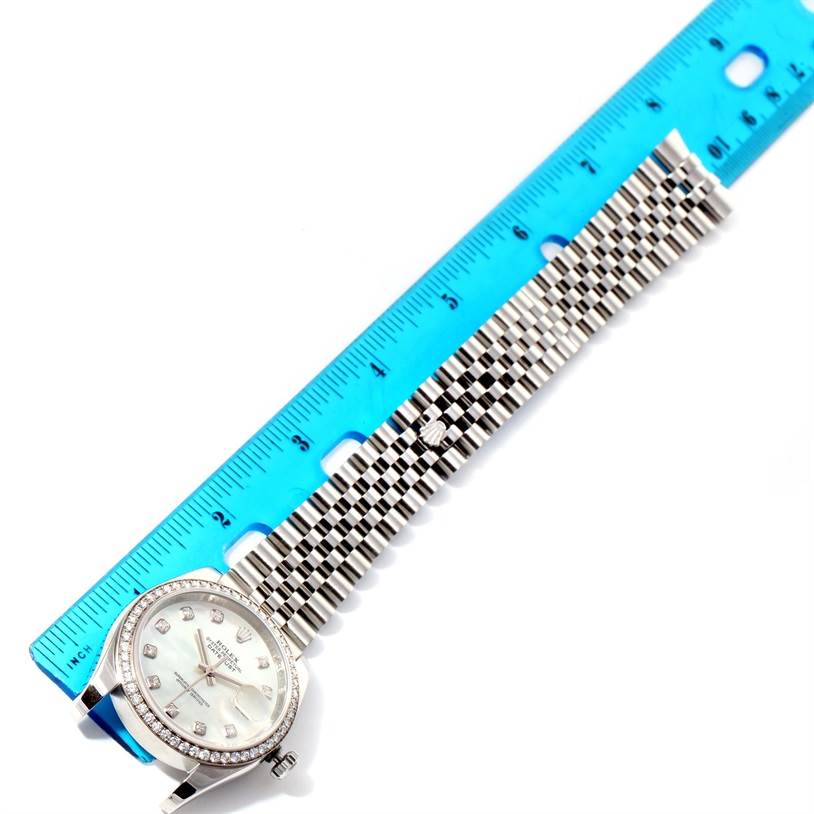 The image shows a Rolex Datejust 116244 Men's Stainless Steel Mother of Pearl Dial 116244 Men's Stainless Steel Mother of Pearl Dial watch laid flat next to a blue ruler, highlighting its face and metal bracelet.