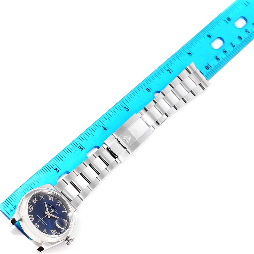 The image shows a Rolex Datejust 116200 Men's Stainless Steel Blue Dial 116200 Men's Stainless Steel Blue Dial watch laid flat with a blue ruler measuring its band length.