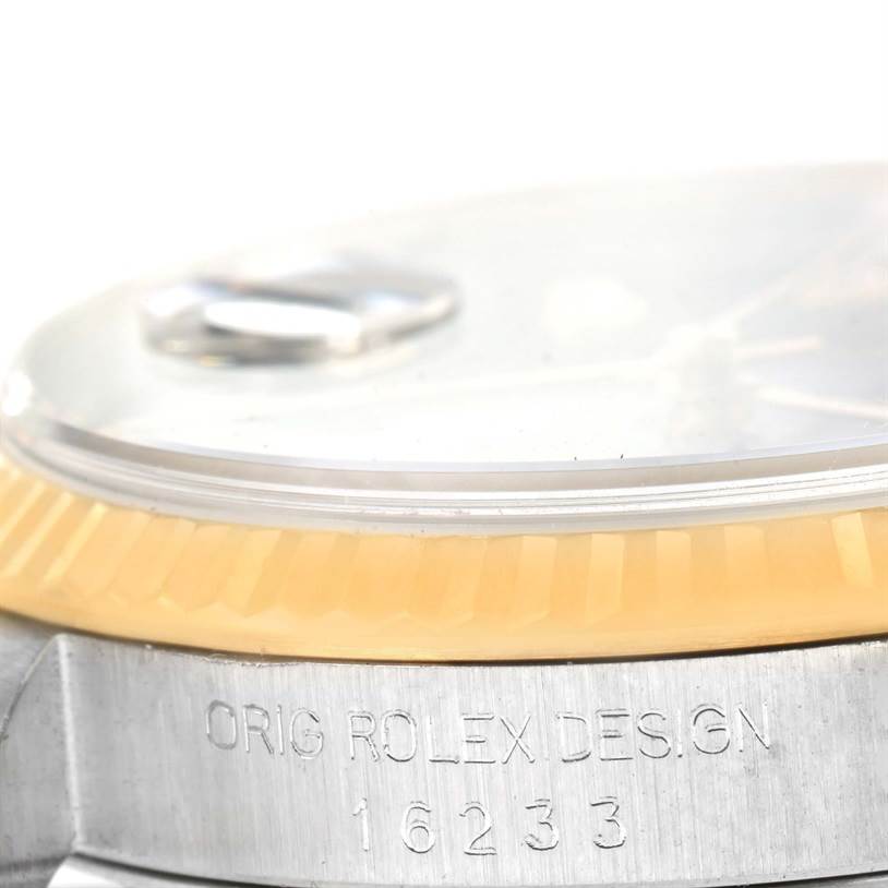 The image shows a close-up of the side view of a Rolex Datejust 16233 Men's Steel and Gold (two tone) Beige Dial 16233 Men's Steel and Gold (two tone) Beige Dial's case, bezel, and part of the crystal with engraved text "ORIG ROLEX DESIGN 16233."