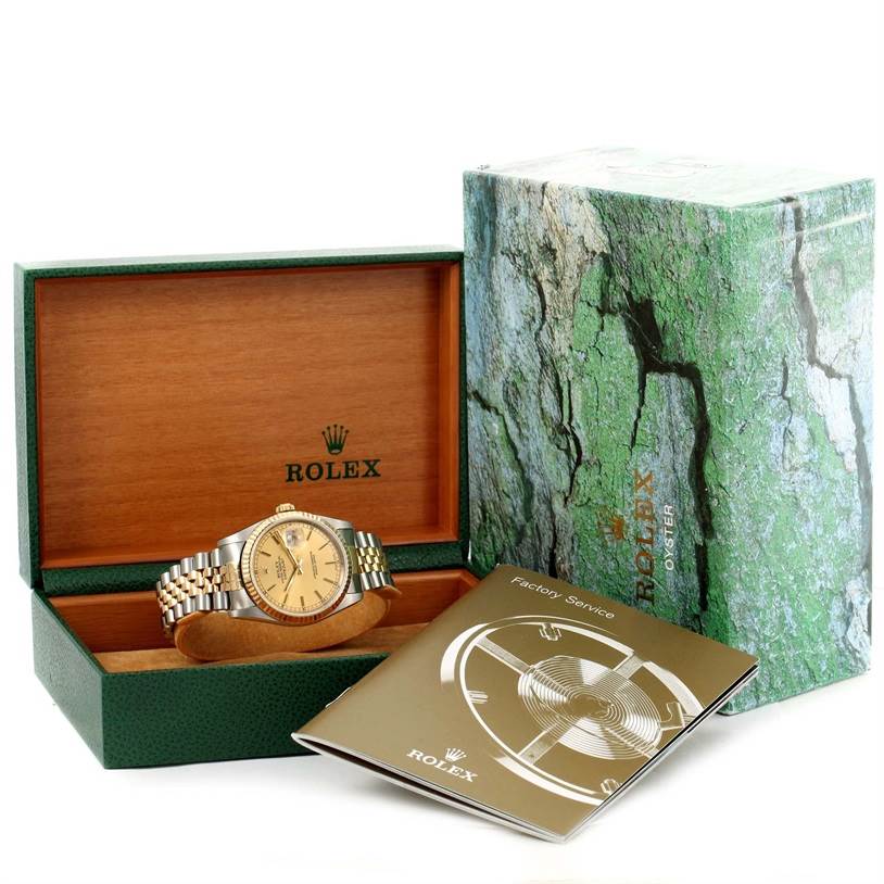 The image shows a Rolex Datejust 16233 Steel and Gold (two tone) Champagne Dial 16233 Steel and Gold (two tone) Champagne Dial watch in its green and wooden box, with a booklet and outer packaging beside it.