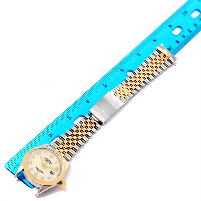 The image shows a Rolex Datejust 16233 Men's Steel and Gold (two tone) Beige Dial 16233 Men's Steel and Gold (two tone) Beige Dial watch laying flat next to a blue ruler, displaying its dial, bracelet, and clasp.
