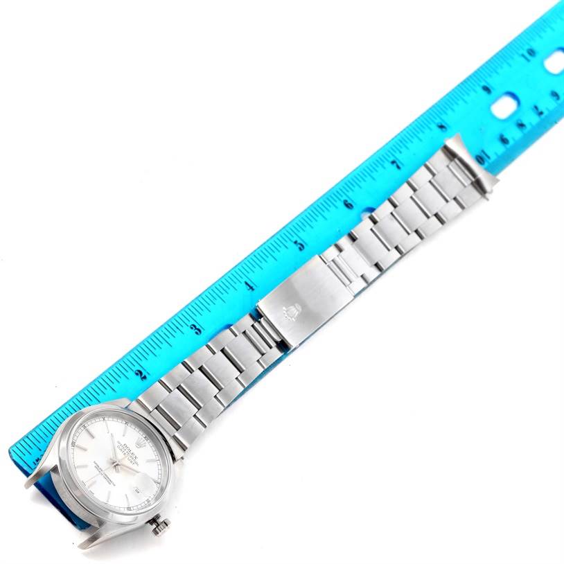 The image shows a Rolex Datejust 16200 Men
s Stainless Steel Silver Dial 16200 Men
s Stainless Steel Silver Dial watch laid flat with a blue ruler measuring its length.