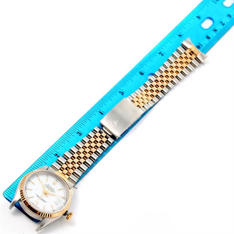 This image shows a Rolex Datejust 16233 Men's Steel and Gold (two tone) White Dial 16233 Men's Steel and Gold (two tone) White Dial watch laid flat with its bracelet extended alongside a blue ruler.