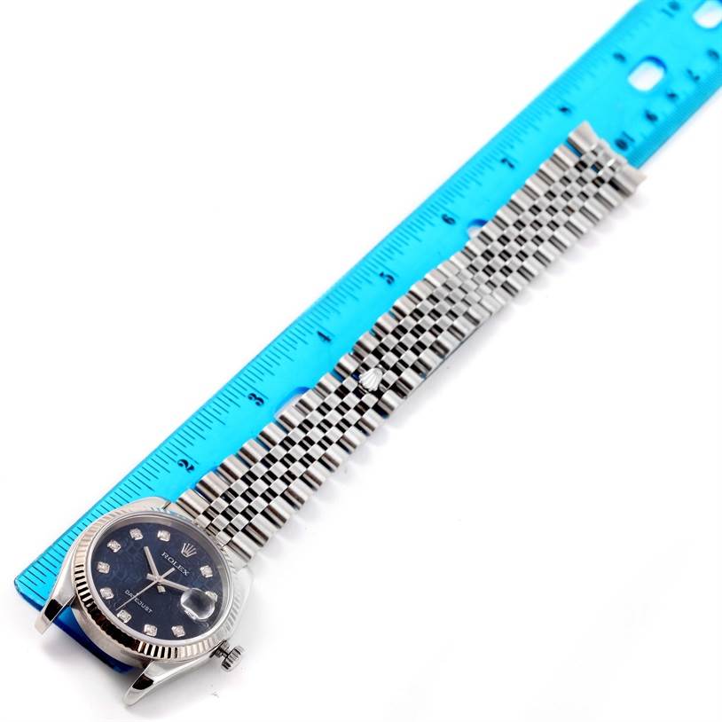 The Rolex Datejust 116234 Men's Stainless Steel Blue Dial 116234 Men's Stainless Steel Blue Dial watch is shown from a top-down angle, with a focus on the face and band next to a blue ruler for scale.