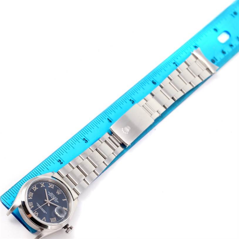 The image shows a Rolex Datejust 16200 Men's Stainless Steel Blue Dial 16200 Men's Stainless Steel Blue Dial watch laid flat with a blue ruler measuring its length, showing the dial, bezel, and bracelet.