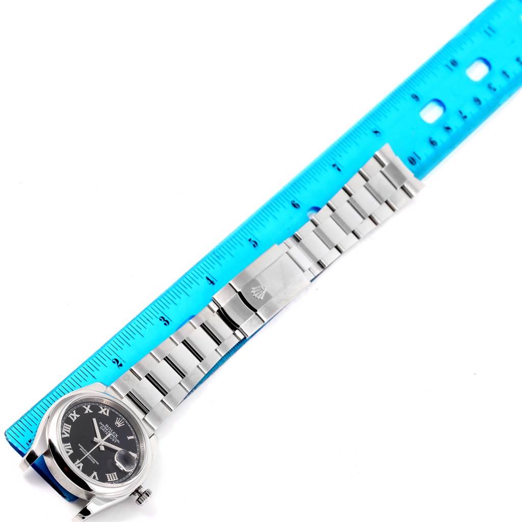 The image shows a Rolex Datejust 116200 Men's Stainless Steel Black Dial 116200 Men's Stainless Steel Black Dial watch laid flat beside a ruler, displaying its face and bracelet in full.