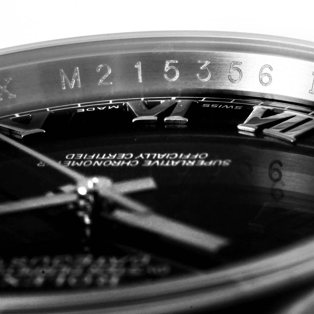 The image shows a macro view of the Rolex Datejust 116200 Men's Stainless Steel Black Dial 116200 Men's Stainless Steel Black Dial watch's dial, hands, Roman numeral markers, and serial number on the rehaut.