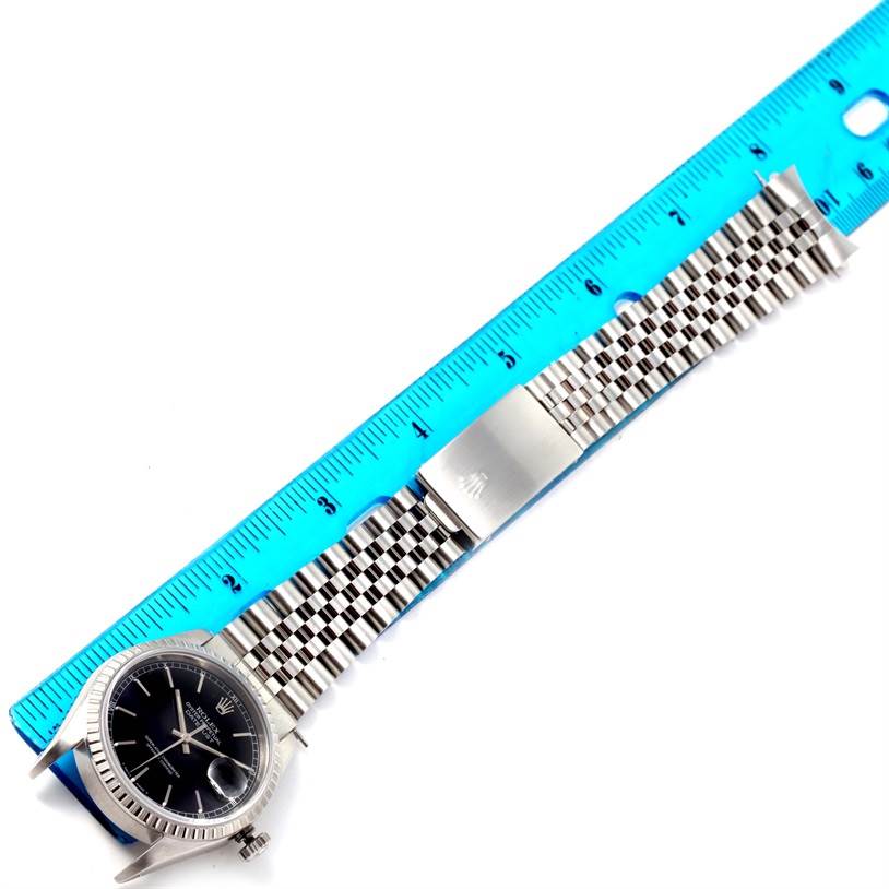 The image shows the Rolex Datejust 16220 Men
s Stainless Steel Black Dial 16220 Men
s Stainless Steel Black Dial watch, including its face, bezel, and band, alongside a measuring ruler for scale.