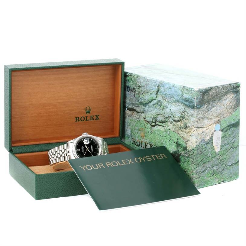 The image shows a Rolex Datejust 16220 Men
s Stainless Steel Black Dial 16220 Men
s Stainless Steel Black Dial watch in an open box with a booklet and outer packaging.