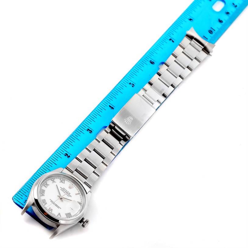 The image shows a top-down view of a Rolex Datejust 16200 Men
s Stainless Steel White Dial 16200 Men
s Stainless Steel White Dial model watch, highlighting its face, bracelet, and clasp alongside a measuring ruler.