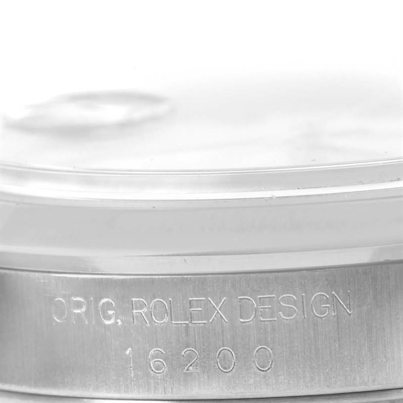 The image shows a close-up angle of the serial number and "ORIG. ROLEX DESIGN" engraving on a Rolex Datejust 16200 Men
s Stainless Steel White Dial 16200 Men
s Stainless Steel White Dial watch.