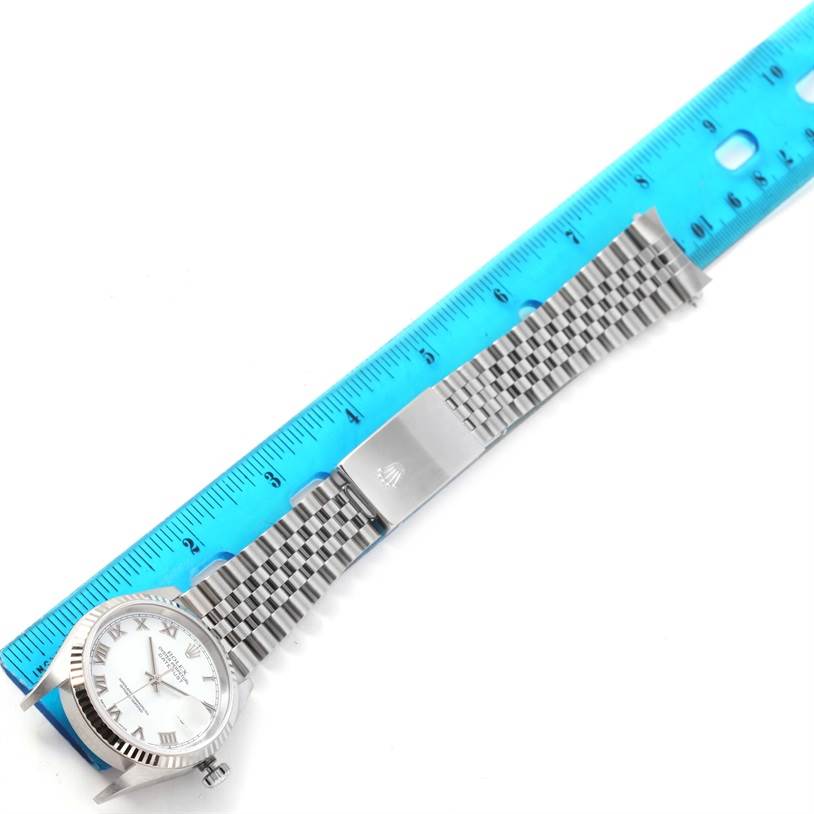 The image shows a Rolex Datejust 16234 Men
s Stainless Steel White Dial 16234 Men
s Stainless Steel White Dial watch laid flat next to a blue ruler, displaying the face, link bracelet, and clasp.