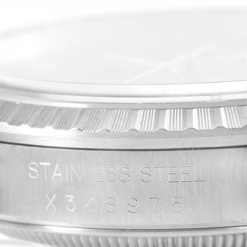 The image shows a close-up view of the side of a Rolex Datejust 16220 Men
s Stainless Steel Black Dial 16220 Men
s Stainless Steel Black Dial watch bezel, highlighting the "STAINLESS STEEL" inscription and serial number.