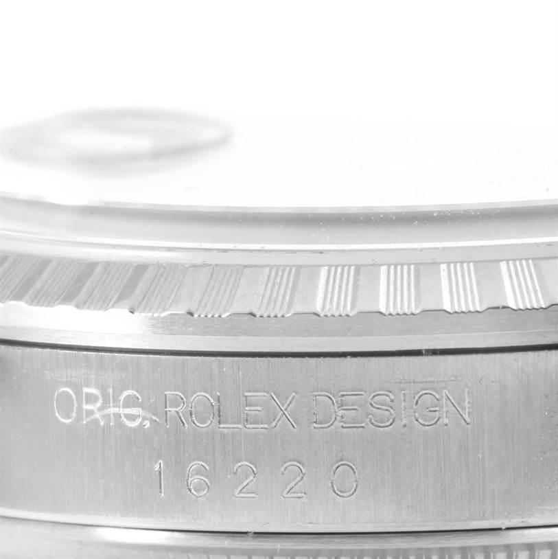 The image shows a close-up of the side of a Rolex Datejust 16220 Men
s Stainless Steel Silver Dial 16220 Men
s Stainless Steel Silver Dial watch case, featuring engravings and a part of the bezel.