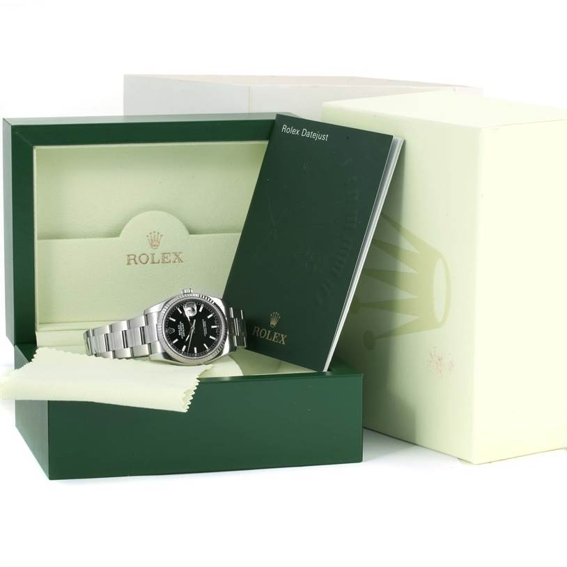 The image shows a Rolex Datejust 116234 Men
s Stainless Steel Black Dial 116234 Men
s Stainless Steel Black Dial watch and its accessories, with the watch laid inside its open green box along with a booklet.