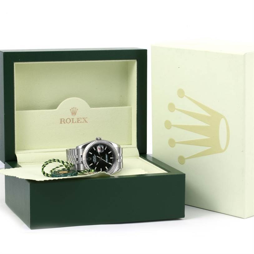 This image shows a Rolex Datejust 116234 Men
s Stainless Steel Black Dial 116234 Men
s Stainless Steel Black Dial watch in an open green and beige Rolex box, highlighting the watch
s face and metal strap clearly.